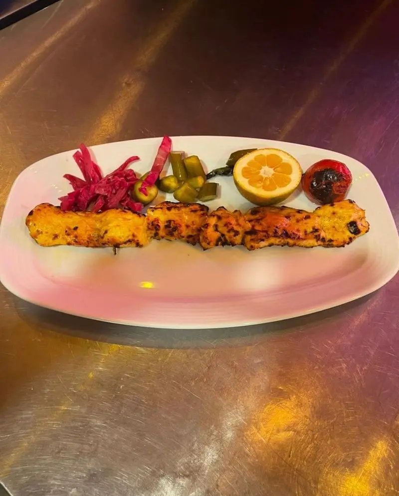 کباب لذیذ جوجه با رنگ و بوی عالی، همراه با مخلفات ترشی کلم و خیار، گوجه کبابی و برش لیمو، انتخابی دلپذیر در کافه رستوران آرشیو.