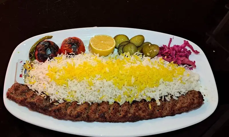 کباب کوبیده لذیذ با برنج زعفرانی و سفید، گوجه کبابی، فلفل سبز، لیمو، خیارشور و کلم قرمز در کافه رستوران آرشیو.