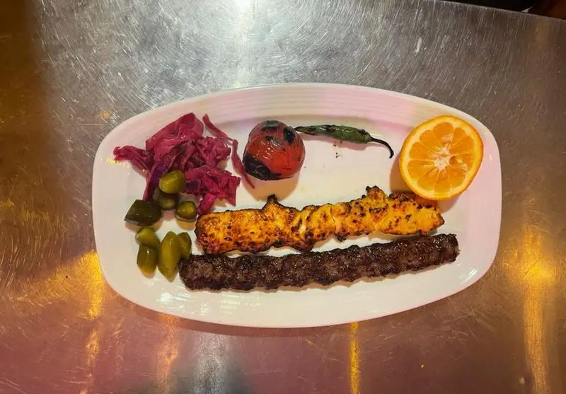 کباب کوبیده و جوجه کباب لذیذ کافه رستوران آرشیو تهران، همراه گوجه کبابی، فلفل، پرتقال و ترشی. غذای اصیل ایرانی.