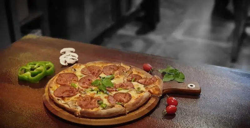 پیتزا سالامی لذیذ کافه رستوران آرشیو با ترکیبات تازه قارچ، فلفل دلمه، گوجه گیلاسی و سبزیجات معطر در منوی غذایی.