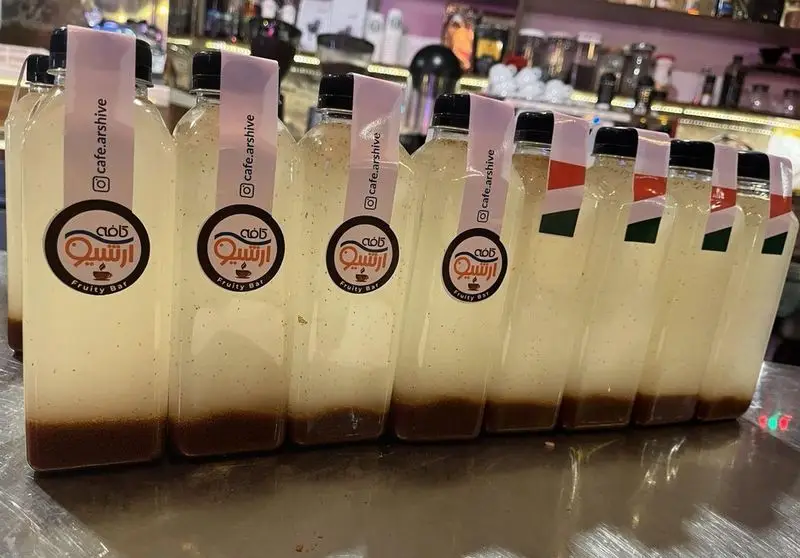 صفی از بطری‌های نوشیدنی خنک و لایه‌لایه با برچسب کافه آرشیو و Fruity Bar، محصولی از کافه رستوران آرشیو.