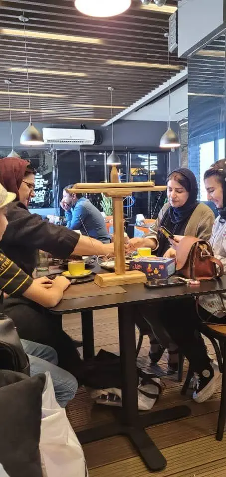 تصویری از مشتریان فودهال نارسیس در حال لذت بردن از نوشیدنی‌های کافه در فضایی آرام و دنج با دکوراسیون چوبی و نورپردازی جذاب.