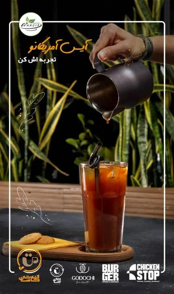 آیس آمریکانو خنک و دلپذیر فودهال نارسیس، با دست در حال ریختن قهوه در لیوان حاوی یخ و بیسکویت. نوشیدنی عالی برای تابستان.