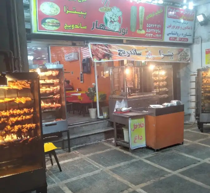 نمای بیرونی فست فود پیتزا نوبهار با کباب ترکی، مرغ بریان و تابلوهای تبلیغاتی پیتزا، ساندویچ و فلافل داغ.