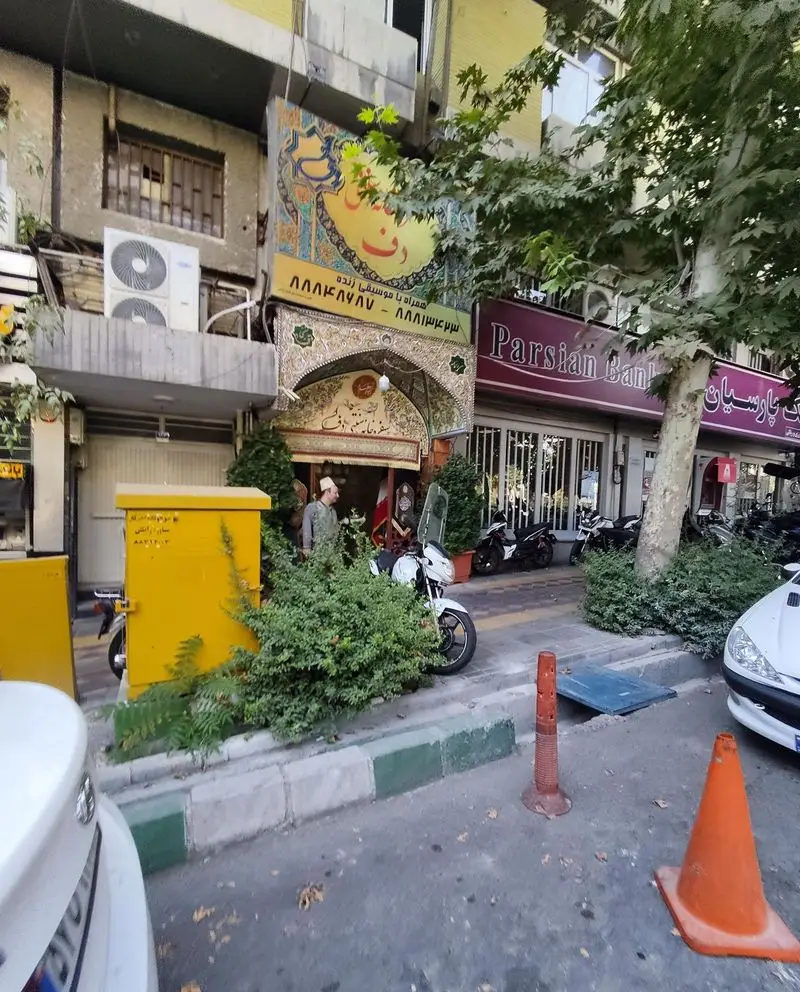 تصویر نمای بیرونی رستوران سنتی دف در تهران، با ورودی مزین، تابلوی "موسیقی زنده" و شعار "سفره‌خانه سنتی دف".