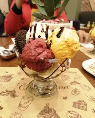 بستنی سه اسکوپ متنوع با طعم‌های وانیل، توت‌فرنگی و انبه، تزئین شده با سس شکلات و کوکی، دسری خوشمزه از کافه ویونا.