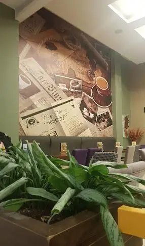 فضای داخلی کافه ویونا با دیوارنگاره جذاب مربوط به قهوه و متون قدیمی، نشان‌دهنده محیطی دنج و مبلمان راحت برای مهمانان.