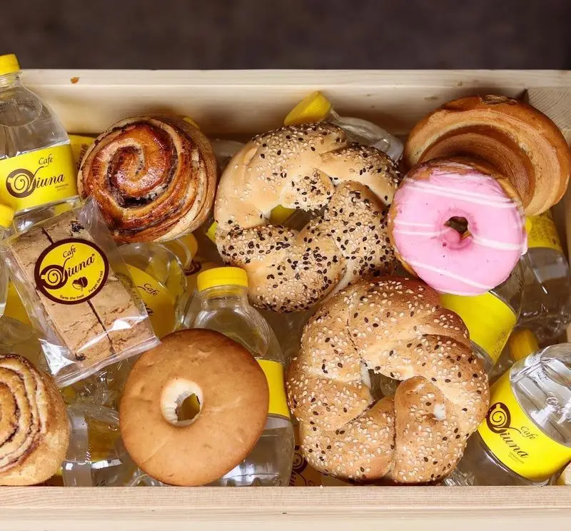 پک پذیرایی کافه ویونا شامل رول دارچین، دونات صورتی، نان‌های کنجدی و نوشیدنی‌های Cafe Viuna برای یک صبحانه یا میان وعده کامل.