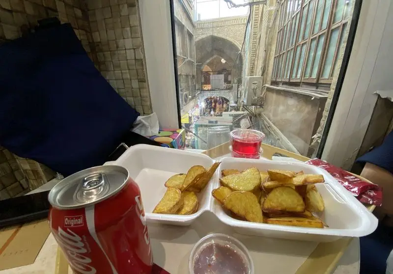 سفارش شمرونی: سیب زمینی تنوری داغ، نوشابه کوکاکولا و نوشیدنی خنک با منظره‌ای چشم‌نواز از بازار سنتی. تجربه دلپذیر در شمرونی.