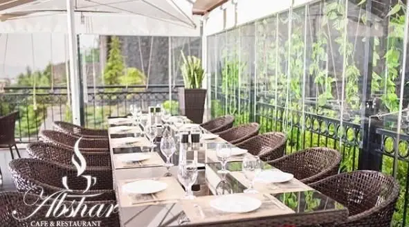 کافی شاپ آبشار: فضای دنج و زیبای تراس با چیدمان کامل میز برای مهمانان، صندلی‌های حصیری راحت و دکوراسیون گیاهی چشم‌نواز.