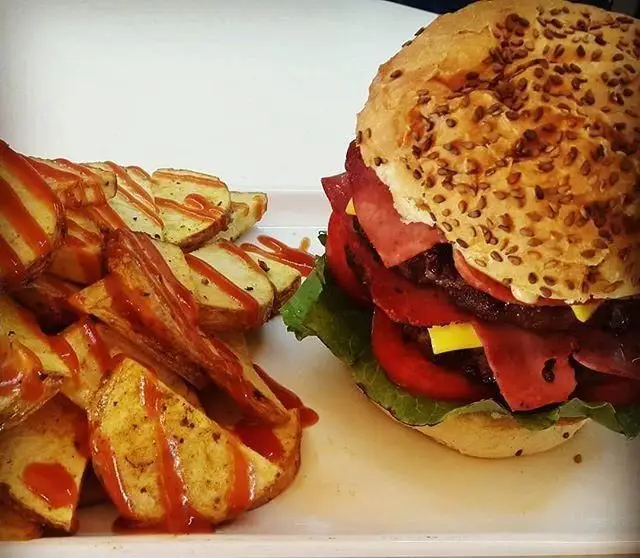 برگر دوبل مخصوص کافی شاپ آبشار با نان کنجدی، کاهو، گوجه، پنیر و کالباس، همراه سیب زمینی تنوری و سس کچاپ لذیذ.