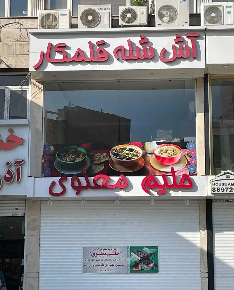 تصویر نمای بیرونی فروشگاه آش شله قلمکار و حلیم معنوی، با ویترینی از غذاهای سنتی ایرانی شامل آش و حلیم آماده سرو.