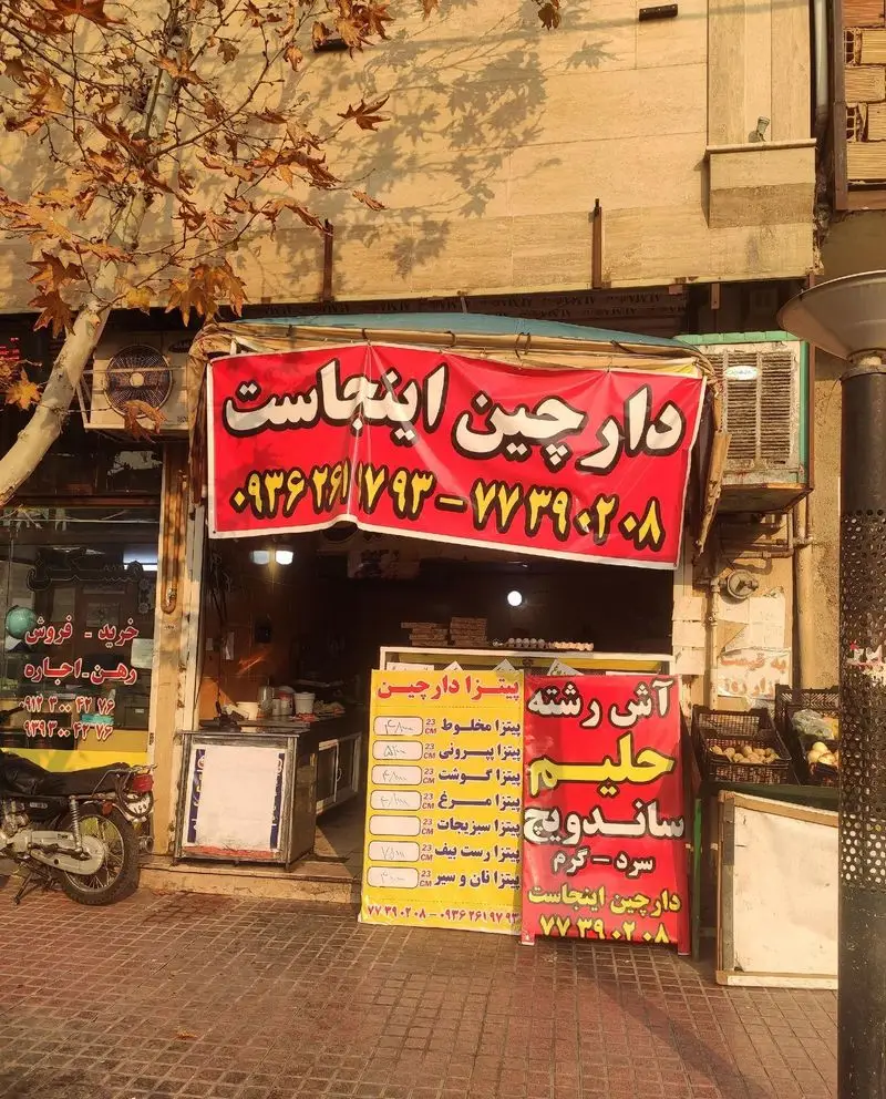 کسب و کار پیتزا و ساندویچ دارچین: نمای بیرونی با منوی متنوع پیتزا، آش رشته، حلیم و انواع ساندویچ سرد و گرم جهت سفارش.