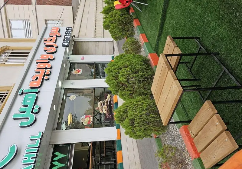 نمای بیرونی رستوران فست فود سوخاری واویجه آهیل با تابلوی مشخص و فضای سبز مصنوعی برای نشستن در فضای باز و لذت بردن از مرغ سوخاری.