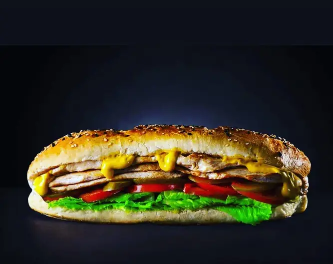 ساندویچ مرغ خوشمزه و پرملات رستوران چدن داغ با نان کنجدی، سس، کاهو و گوجه فرنگی، مناسب سفارش آنلاین و حضوری.