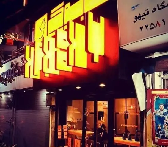 نمای بیرونی و تابلو نورانی کسب و کار "بازیلیکو آریانو" در شب، با ورودی شیشه‌ای و طرح‌های مدرن و جذاب برای مشتریان.