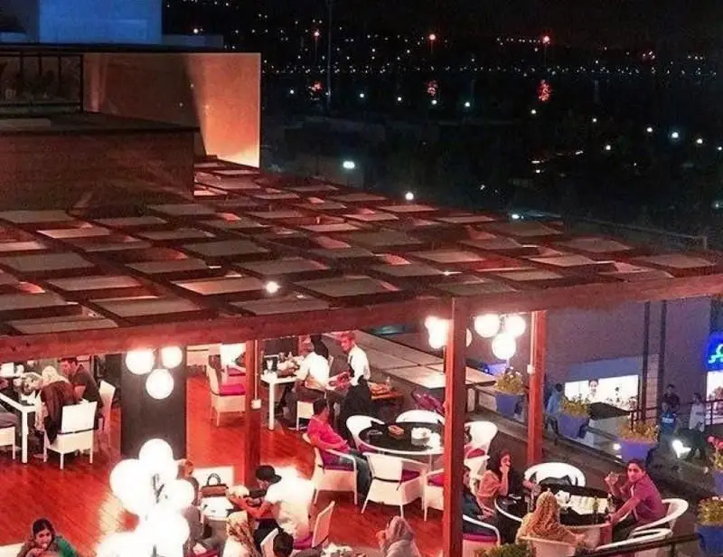 رستوران ایرانی ته دیگ: روف گاردن دنج و زیبا در شب با منظره شهر، مناسب برای شامی دلنشین در فضای باز و مدرن