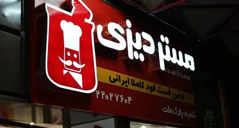 تابلوی روشن رستوران مستر دیزی در شب با لوگوی سرآشپز و نام شعبه پارک ملت، اولین فست فود کاملا ایرانی.