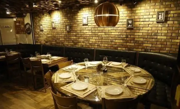 تصویری از فضای داخلی گرم و دلنشین رستوران ایتالیایی آلین. دکوراسیون با دیوار آجری، میزهای شیک و نورپردازی جذاب برای تجربه‌ای خاص.