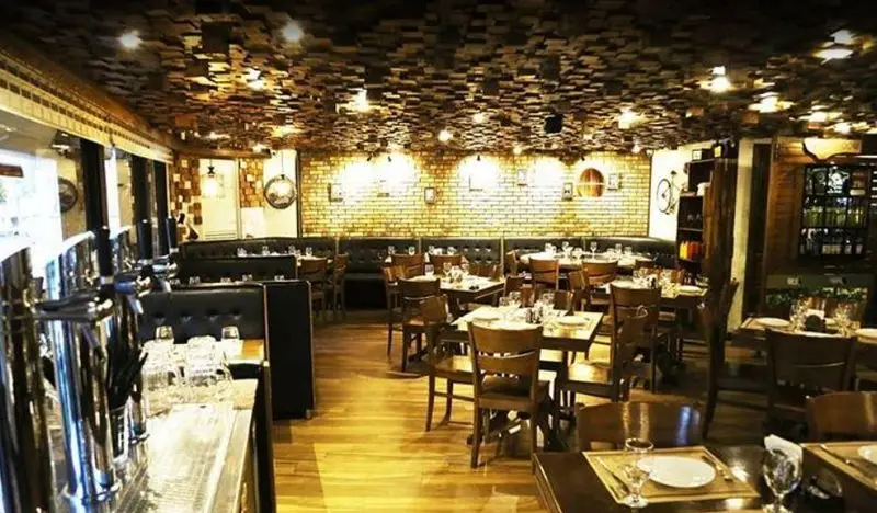 فضای داخلی دنج و شیک رستوران ایتالیایی آلین با دیوارهای آجری، سقف چوبی خاص و چیدمان زیبای میز و صندلی‌ها برای تجربه غذایی دلنشین.