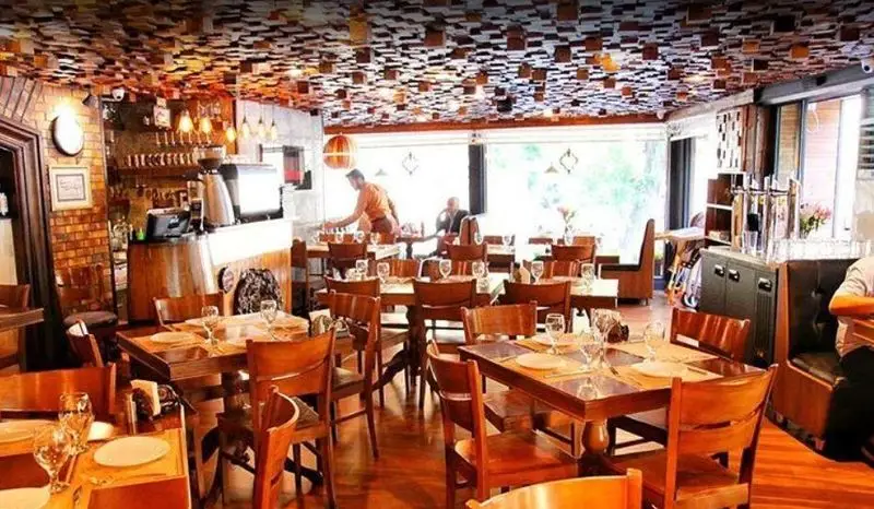 نمایی از فضای داخلی رستوران ایتالیایی آلین با میز و صندلی‌های چوبی، دکوراسیون گرم و سقف چوبی خاص. مکانی دلنشین برای صرف غذا.