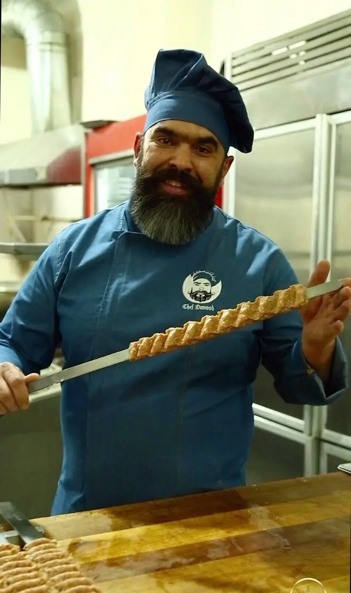 تصویری از سرآشپز باتجربه گل زعفرون، استاد تهیه کباب‌های لذیذ ایرانی. آماده‌سازی کباب کوبیده با بهترین مواد و زعفران ناب.