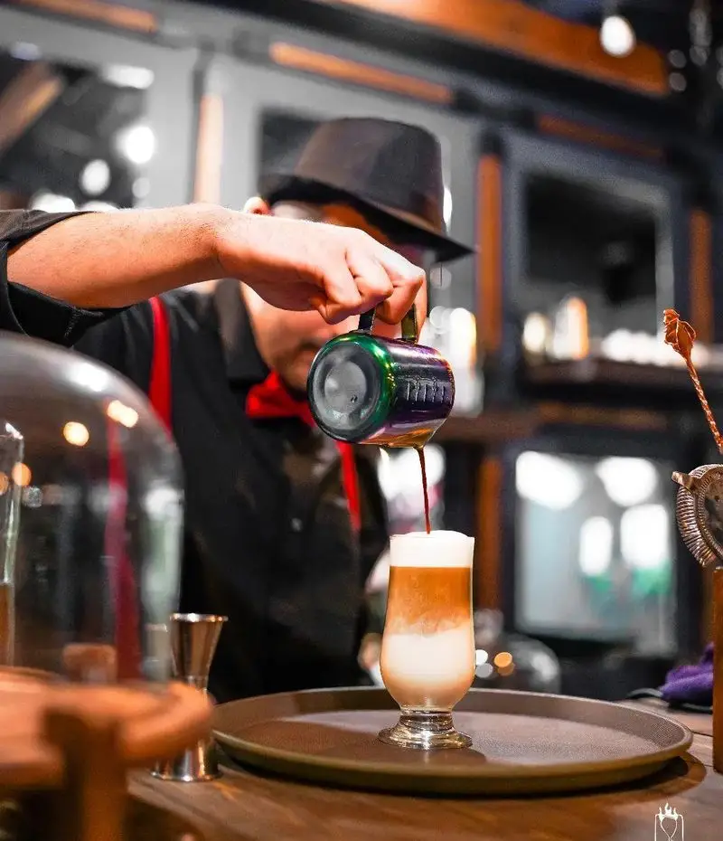 باریستای حرفه ای جیلیزویلیز پیروزی در حال تهیه لاته چندلایه خوشمزه با دقت و ظرافت. تجربه‌ای دلنشین از نوشیدنی‌ها.