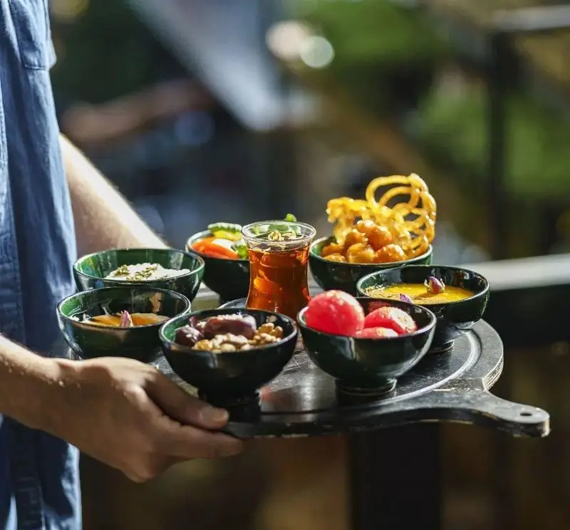 سینی پذیرایی ویژه کافه هاگ: چای، خرما، شیرینی، دسر، و مزه‌های سنتی و تازه. لذت طعم‌های اصیل در فضایی دلنشین.