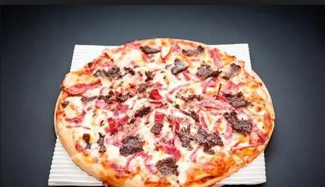 تصویر یک پیتزای بزرگ و پر پنیر با گوشت‌های لذیذ از رستوران ایران ایتالیا، غذایی بی‌نظیر برای تجربه طعم واقعی ایتالیا.