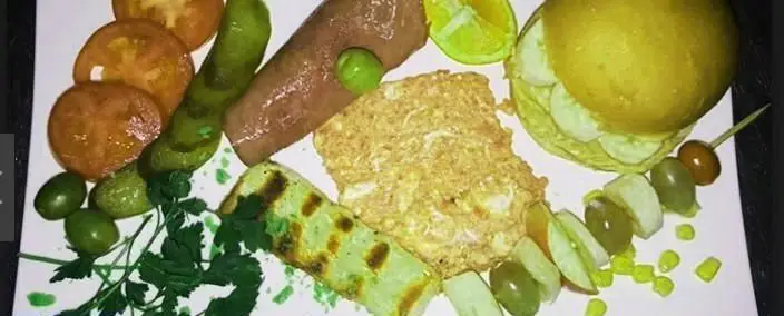 سینی صبحانه کامل و متنوع رستوران ایران ایتالیا: املت، سوسیس، گوجه، خیار، زیتون، فلفل، میوه و نان. یک وعده غذایی دلپذیر.