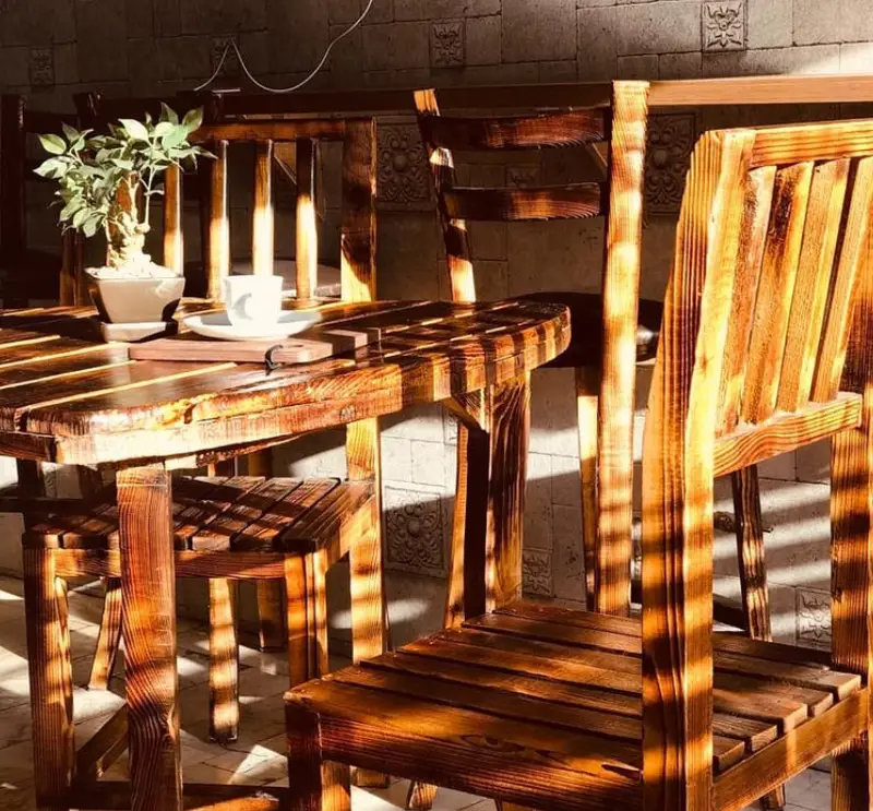 میز و صندلی چوبی کافه آفر با فضای دلنشین و نور آفتاب، ایده‌آل برای لذت بردن از قهوه در محیطی آرام.