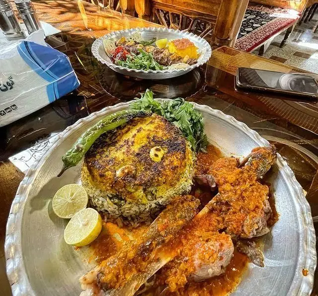 رستوران سنتی آرامش: سفره ای رنگین از غذای اصیل ایرانی شامل پلو ماهی یا ته چین و خوراک گوشت گوسفند با چاشنی لیمو.