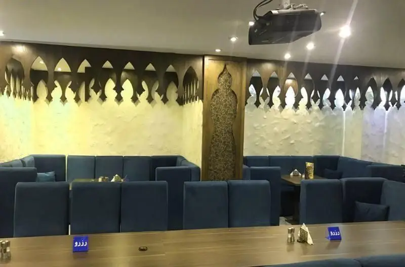 فضای داخلی رستوران رستاک با دکوراسیون سنتی و مبلمان آبی رنگ، میزهای چوبی و دیوارکوب‌های تزئینی، محیطی دنج و شیک را برای مهمانان فراهم کرده است.