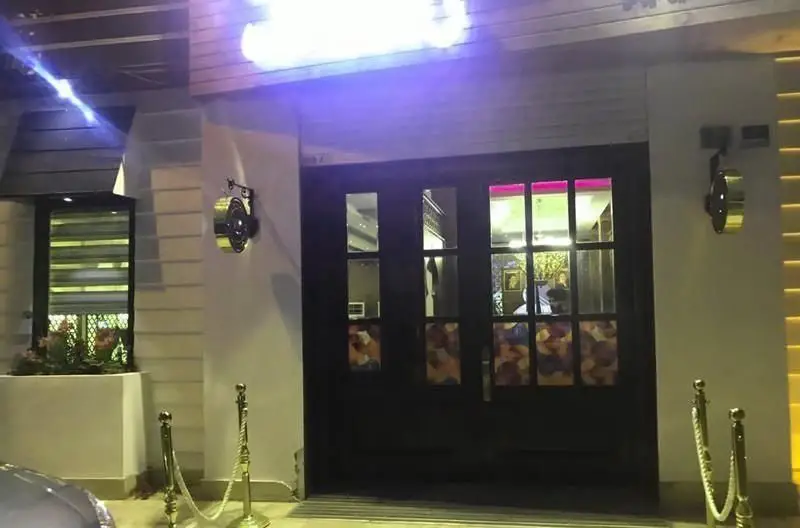 نمای شبانه و لوکس ورودی رستوران رستاک با نورپردازی بنفش و گرم، درهای شیشه‌ای و چوبی، مناسب برای تجربه غذایی دلنشین.