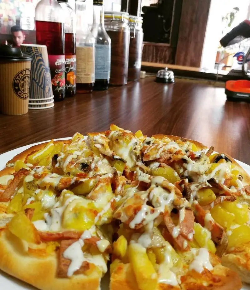 پیتزا سیب زمینی و ژامبون لذیذ در کافه رستوران دنج، همراه با نوشیدنی‌ها و محیطی دلنشین. تجربه طعم بی‌نظیر.