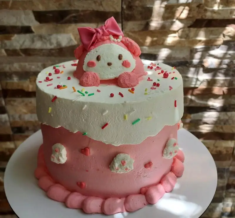 کیک فانتزی و زیبای ماریا با تم صورتی و سفید، تزیینات دلنشین عروسک My Melody، قلب‌ها و اسپرینکل‌های رنگی برای جشن شما.