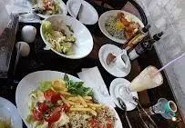 نمایی از منوی متنوع و غذاهای خوشمزه سفره خانه هنرمندان شامل سالاد، سیب‌زمینی، نوشیدنی و دیگر خوراک‌ها در محیطی جذاب و خانوادگی.