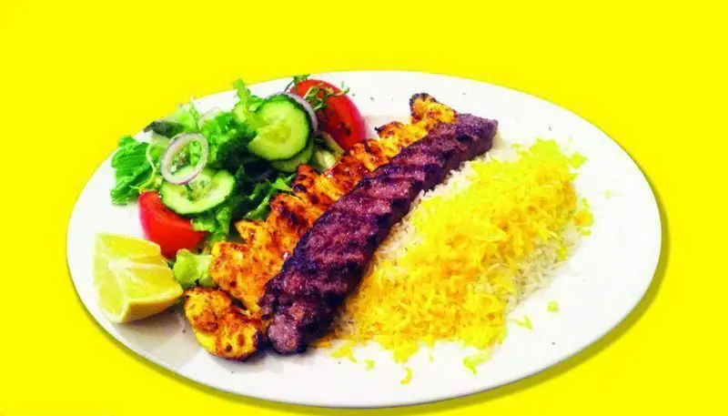 چلوکباب کوبیده و جوجه کباب لذیذ ایرانی با برنج زعفرانی، سالاد تازه و لیمو. غذای اصیل ایرانی در رستوران لوکس