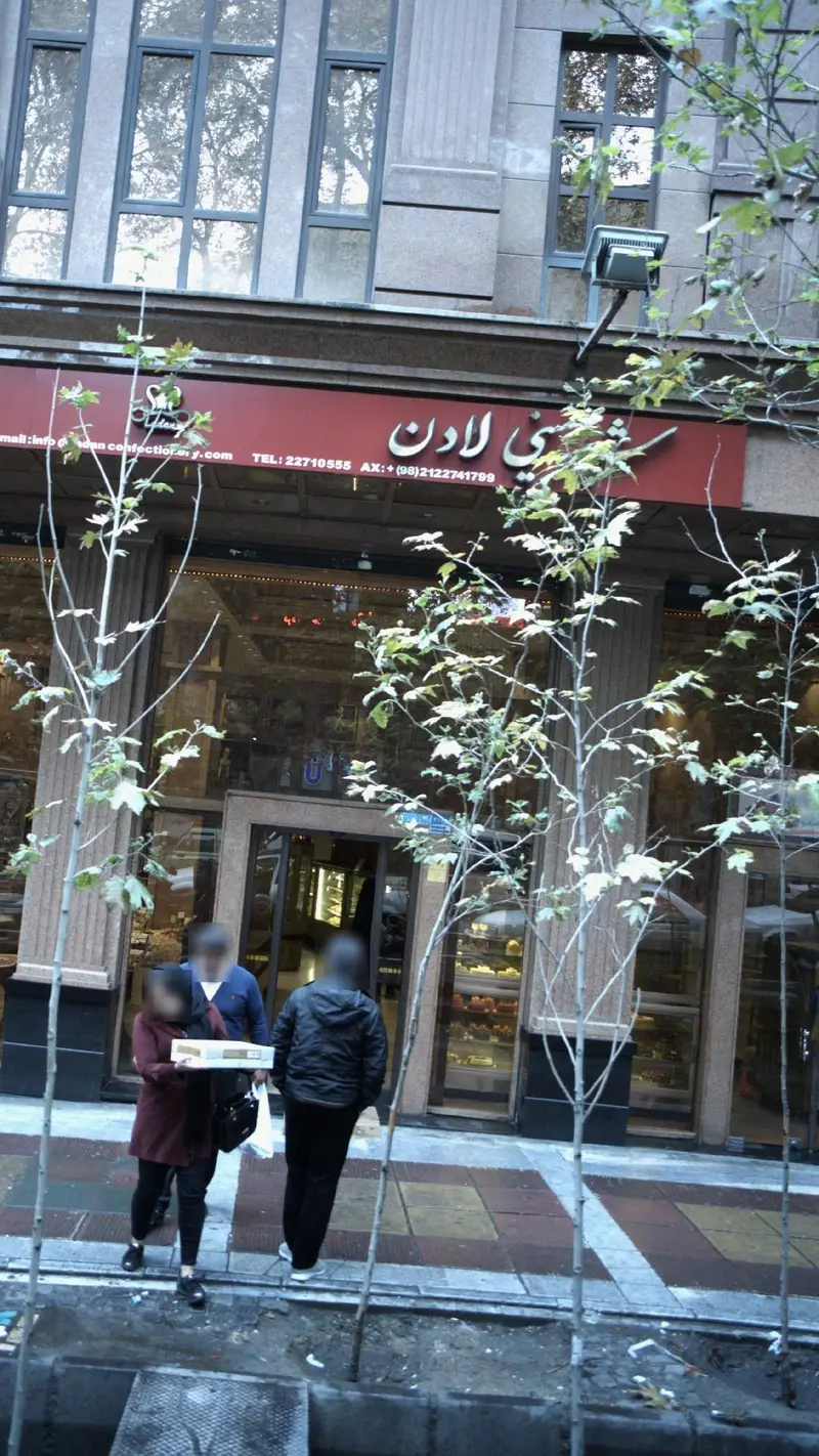 نمای بیرونی شیک و جذاب شیرینی فروشی لادن در تهران با تابلوی مشخص، مشتریان در حال خرید و ویترین پر از کیک و شیرینی تازه.
