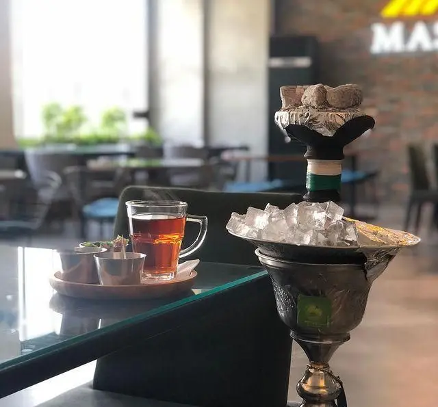 تصویری جذاب از قلیان یخی با زغال داغ و چای تازه دم در کافه رستوران مستان، انتخابی عالی برای لحظاتی آرامش‌بخش.