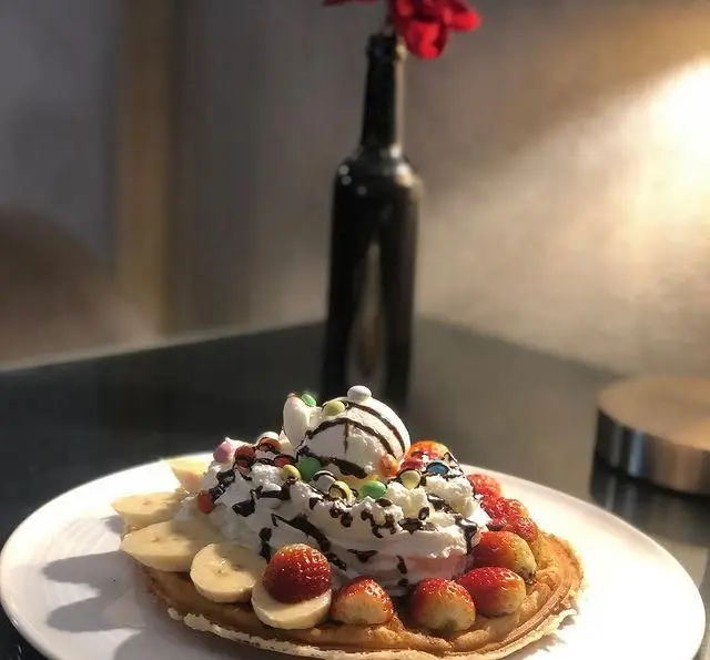 وافل لذیذ کافه رستوران مستان با بستنی، خامه، توت فرنگی، موز، سس شکلات و آبنبات‌های رنگی، یک انتخاب عالی.