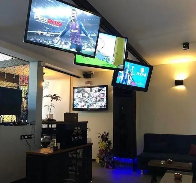 دکوراسیون داخلی کافه رستوران مستان با تلویزیون‌های متعدد پخش‌کننده ورزش، بازی و سرگرمی، میز پذیرش و فضای راحت.