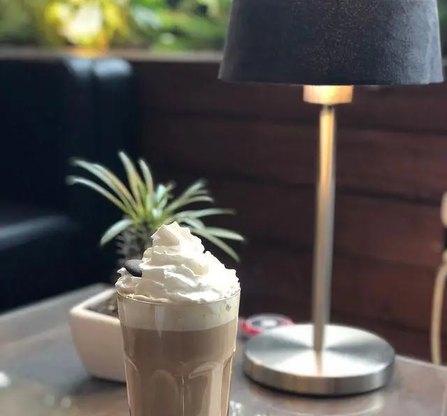 تصویری زیبا از یک نوشیدنی خنک و دلپذیر با خامه فراوان، در فضایی گرم و دلنشین کافه رستوران مستان، با دکوری شیک و مدرن.