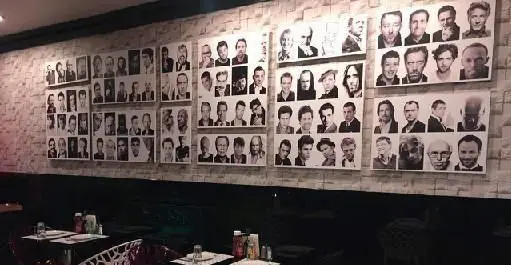 دکوراسیون شیک و فضای دلنشین رستوران ایتالیایی مانلی با دیوار گالری عکس‌های سیاه و سفید از افراد مشهور، محیطی آرامش‌بخش برای تجربه غذا.