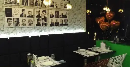 فضای داخلی مدرن رستوران ایتالیایی مانلی با دیواری از پرتره‌های سیاه و سفید، میزهای چیده شده و بالون‌های قلبی شکل، محیطی دلنشین برای صرف غذا.