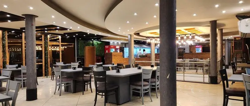 نمایی از محیط داخلی پیتزا سه فر، یک پیتزا فروشی مدرن با دکوراسیون چوبی و نورپردازی جذاب، آماده پذیرایی از مشتریان.