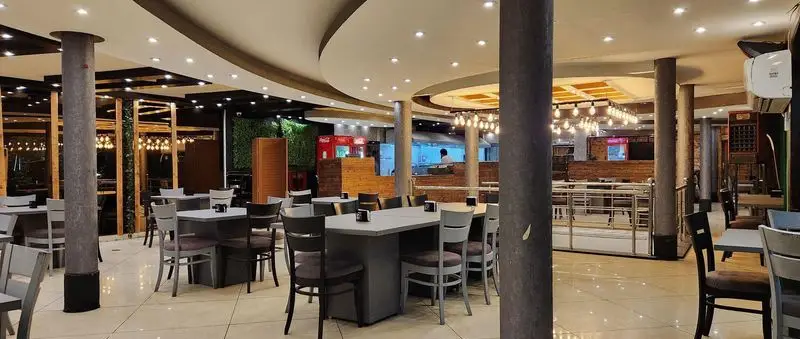 فضای داخلی شیک و مدرن رستوران پیتزا سه فر با نورپردازی دلپذیر و میز و صندلی‌های راحت، آماده پذیرایی از مشتریان.