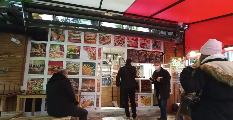 کسب و کار وارطان لند، رستورانی شلوغ با نمای جذاب از غذاهای لذیذ مانند پیتزا، برگر و ساندویچ آماده سرویس به مشتریان.