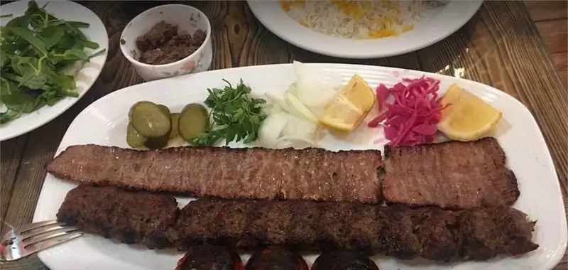 کباب کوبیده و برگ لذیذ رستوران سنتی گلستانه با برنج زعفرانی، مخلفات تازه شامل خیارشور، پیاز، سبزی و لیمو