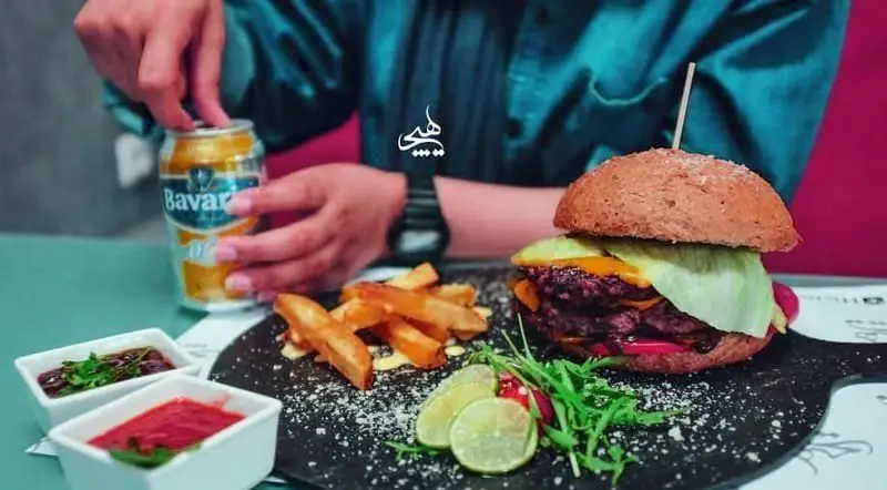 همبرگر ویژه دوبل گوشت با پنیر، کاهو و سس، سیب زمینی سرخ کرده و نوشیدنی در کافی شاپ هیچ. تجربه‌ای لذت‌بخش.